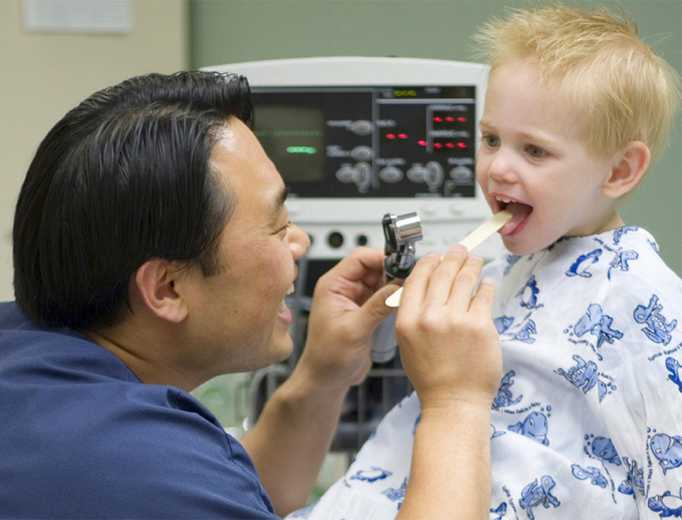 Pediatrician examining child's throat with otoscope.